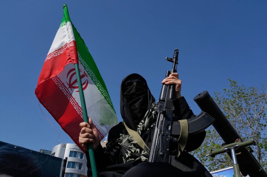 17日、イラン・テヘランで開かれた親政府集会で、イランのバシジ民兵隊所属の女性隊員が銃とイラン国旗を持っている。［AP＝聯合ニュース］