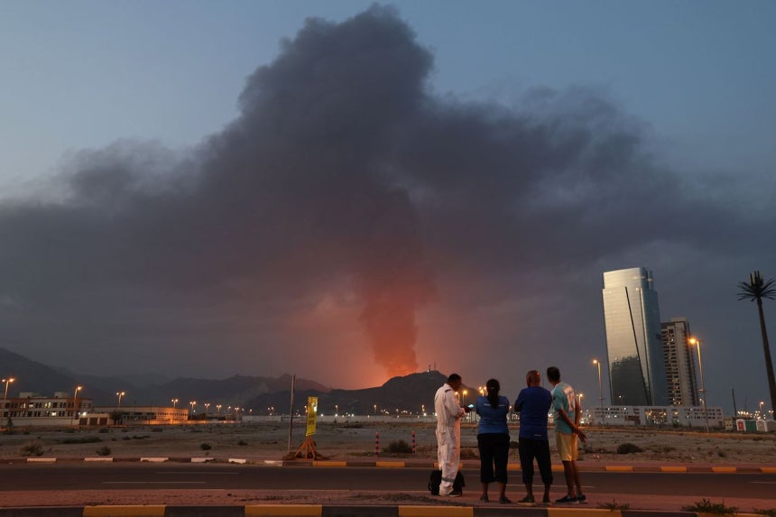 今年3月3日（現地時間）、アラブ首長国連邦（UAE）フジャイラ石油工業地帯で爆発が発生した後、黒煙が立ち上る様子を外国人労働者らが見守っている。AFP＝聯合ニュース