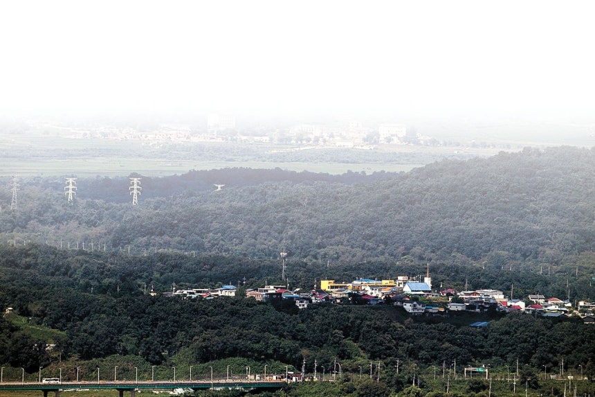 京畿道坡州市郡内面（キョンギド・パジュシ・クンネミョン）の統一村。写真は坡州市の接境地域から眺めた西部戦線非武装地帯（DMZ）一帯で、統一村（写真下部の集落）が開城（ケソン）工業団地へ続く送電塔越しに北朝鮮の村と向かい合う様子。聯合ニュース