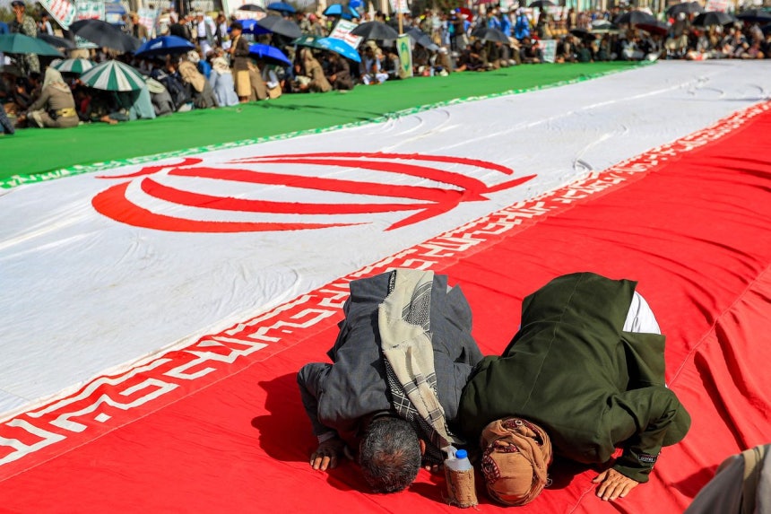 イエメンの首都サアナで16日、フーシ派の隊員がイラン国旗の上で祈りを捧げている。［写真 AFP＝聯合ニュース］