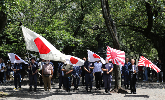 昨年8月15日、東京靖国神社を訪れた人たちが旭日旗と日章旗を持っている。 ［聯合ニュース］