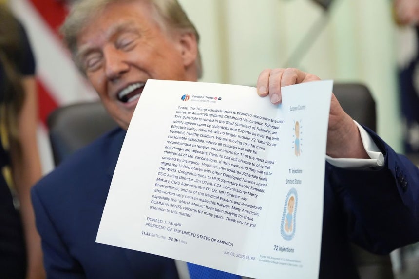 トランプ米大統領が10日（現地時間）、ホワイトハウスで小児向けワクチンの定期接種推奨対象を従来の18種類から11種類の疾病に縮小する内容の大統領令に署名した後、関連のSNS投稿を見せながら笑っている。 ［AP＝聯合ニュース］