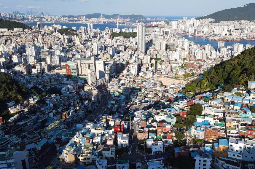 峨嵋洞（アミドン）碑石村の上空から見下ろした釜山（プサン）港の全景。右側の赤い橋が影島大橋（ヨンドデギョ）で、橋を渡ると影島（ヨンド）だ。写真中央の山が竜頭山（ヨンドゥサン）で、竜頭山の左側の山が伏兵山（ポクピョンサン）だ。竜頭山と伏兵山の間を直線に延びる道路が大庁路（テチョンノ）だ。大庁路の海側の端が釜山港で、陸側の端に臨時首都記念館がある。ソン・ミンホ記者