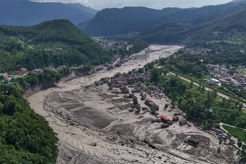 26日（現地時間）、ネパールで鉄砲水が発生した後、川沿いの住宅が泥水に浸かっている。［AP＝聯合ニュース］