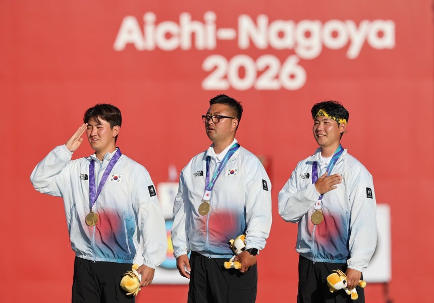 2日、2026年愛知・名古屋アジア大会アーチェリー・リカーブ男子団体戦で金メダルを獲得した韓国のキム・ジェドク（左から）、キム・ウジン、イ・ウソクが表彰台で国旗に敬礼している。［聯合ニュース］