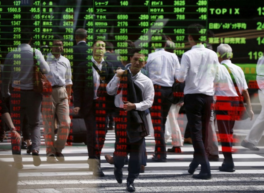 東京の証券会社の株価モニターに通行人の姿が映っている。［写真 ロイター＝聯合ニュース］